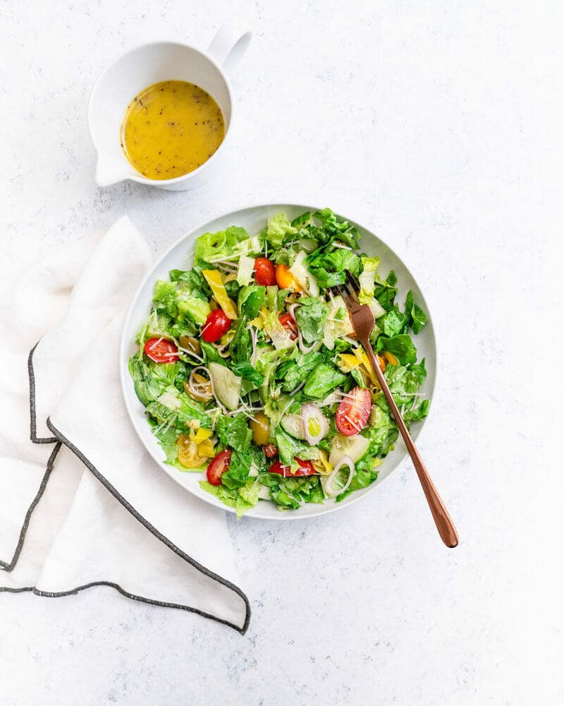 Chopped salad in white bowl with napkin and Italian dressing