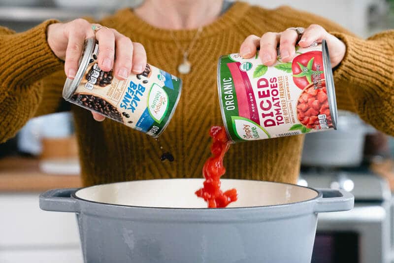 Pouring beans and tomatoes into a pot