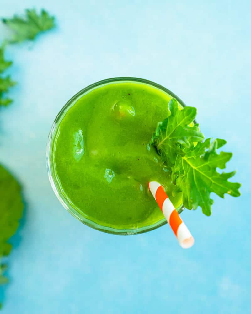 Kale Smoothie recipe in a glass with straw and kale leaf garnish.